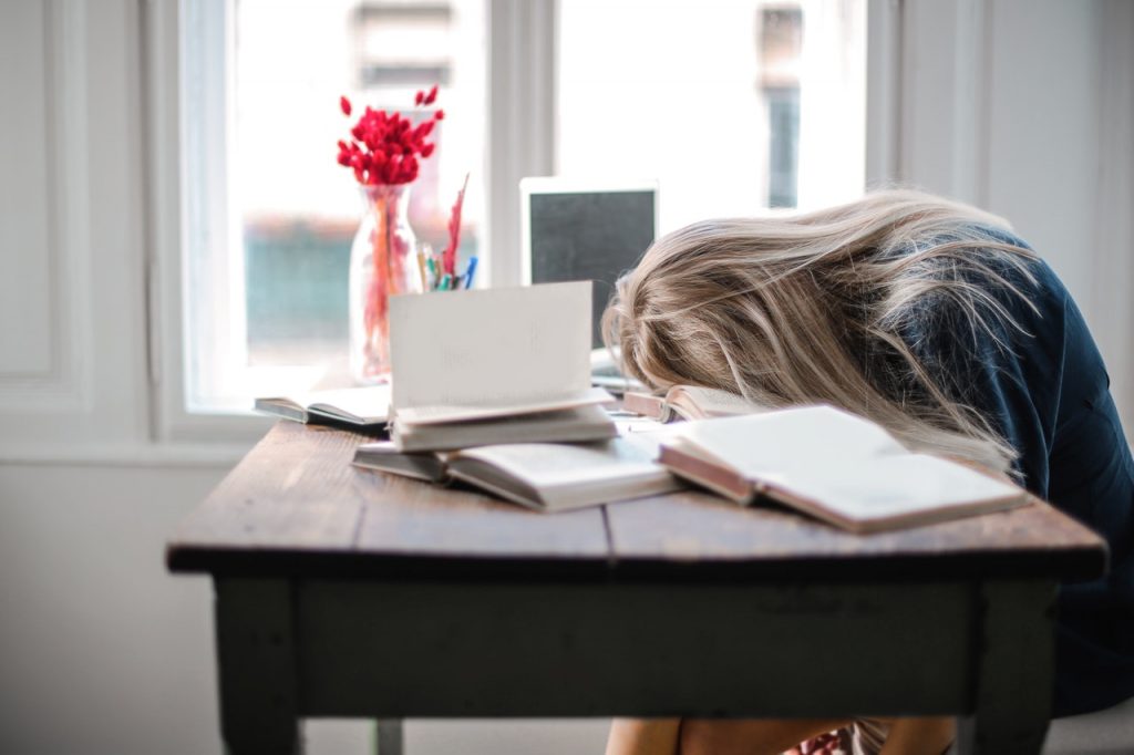 Tired woman leaning her head on table after studying.